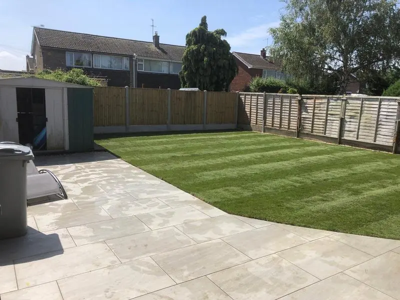 A customer's back garden with a new patio and a freshly striped lawn